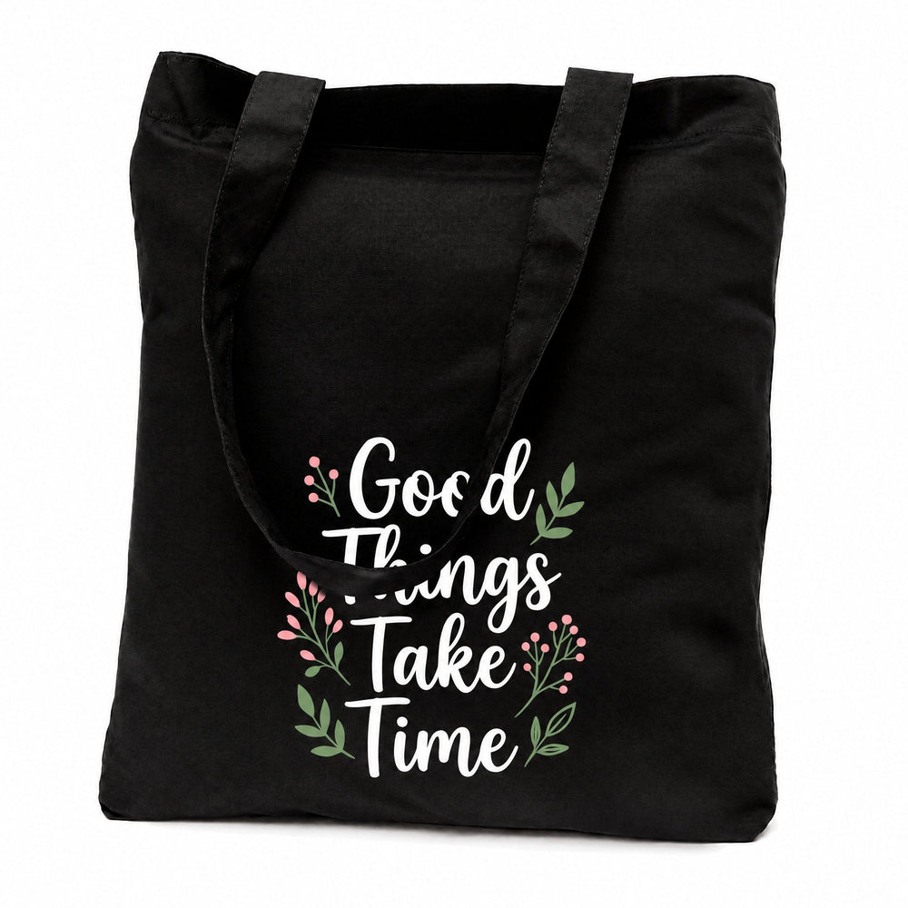Black cotton tote bags printed with 'Good Things Take Time' in white script framed by pink and green sprigs